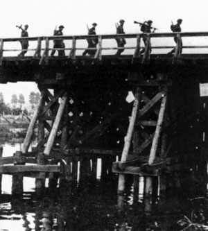 Guards Armoured Division infantry cross a wooden bridge