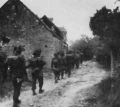 British infantry advance pass some farm buildings