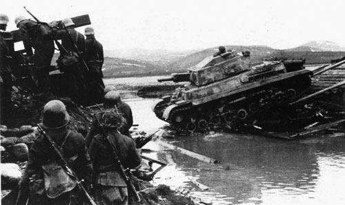 Turan II tank crosses a river over a destroyed bridge.