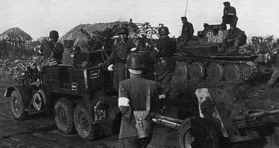 A Krupp truck towing a 40mm Anti-tank gun, in the background is a Panzer 38(t)