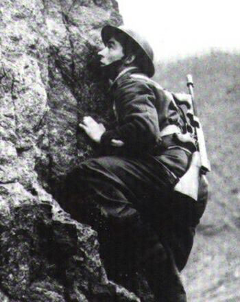 Commando climbing cliff