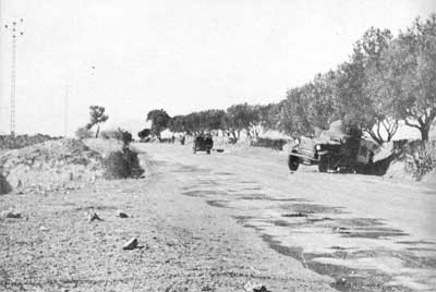A Recon Jeep passes a knocked out French Armoured Car