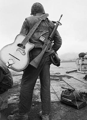 An American G.I. with his slung M16 and guitar awaits evacuation