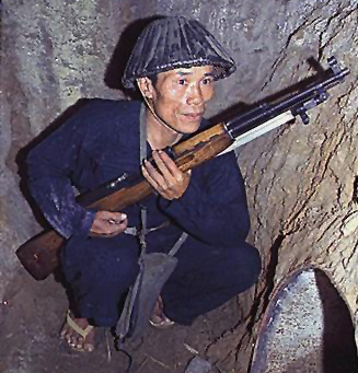 A Vietnamese Guerrilla fighter shelters in a tunnel wthi his SKS carbine